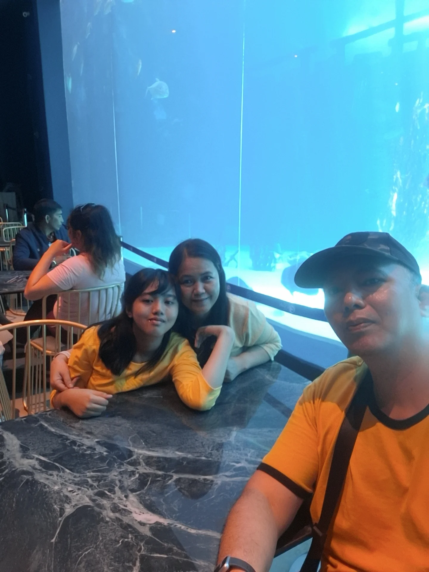 Giovanni Carlo Bagayas and family at a cafe table next to a large blue aquarium tank at Gusto Food Hall, Cebu Ocean Park