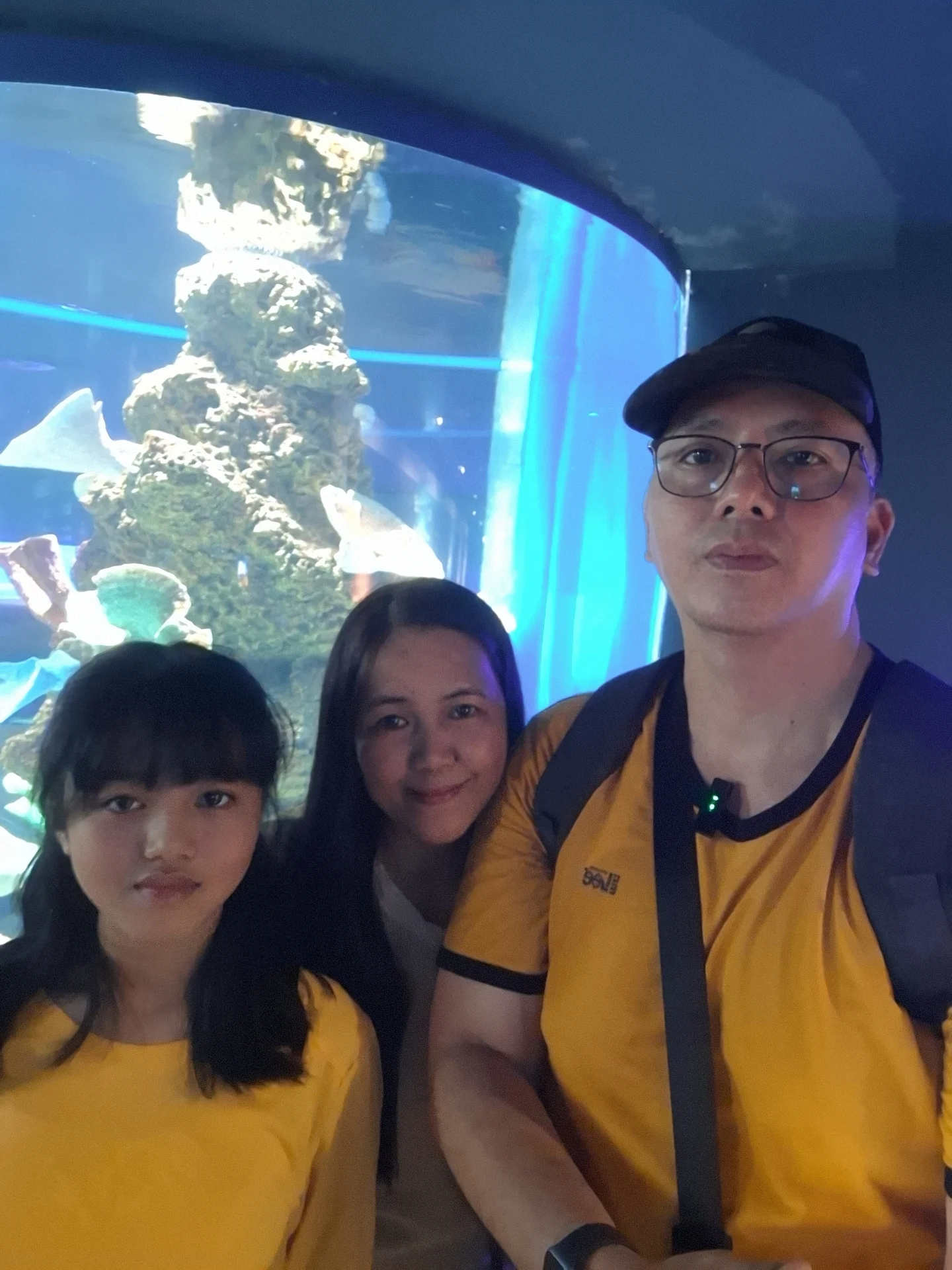 Family close-up selfie in front of a vibrant coral reef tank display at Cebu Ocean Park