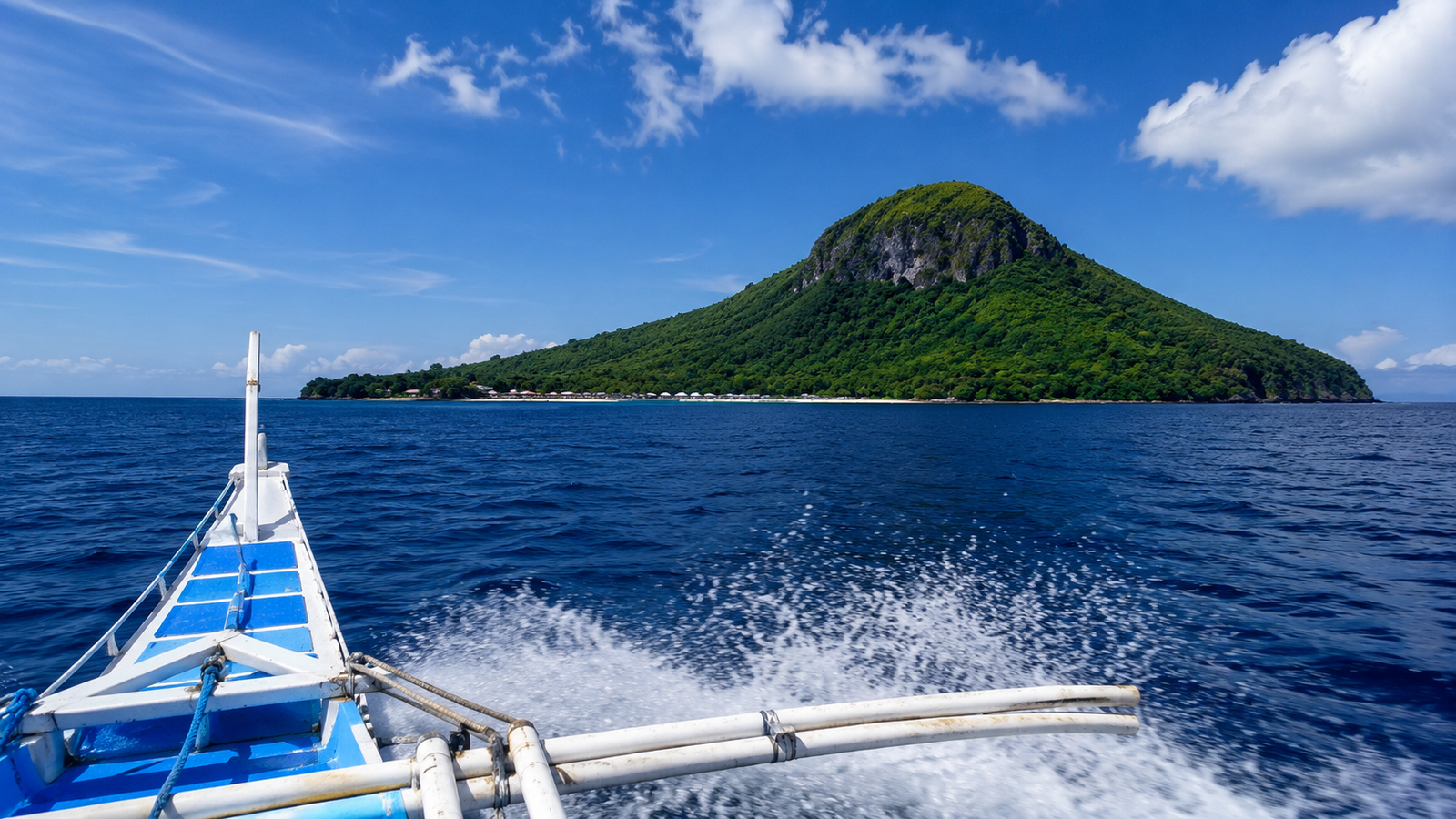View from a bangka outrigger boat crossing to Apo Island — open sea with spray and Apo Island's volcanic peak visible on the horizon Negros Oriental Philippines
