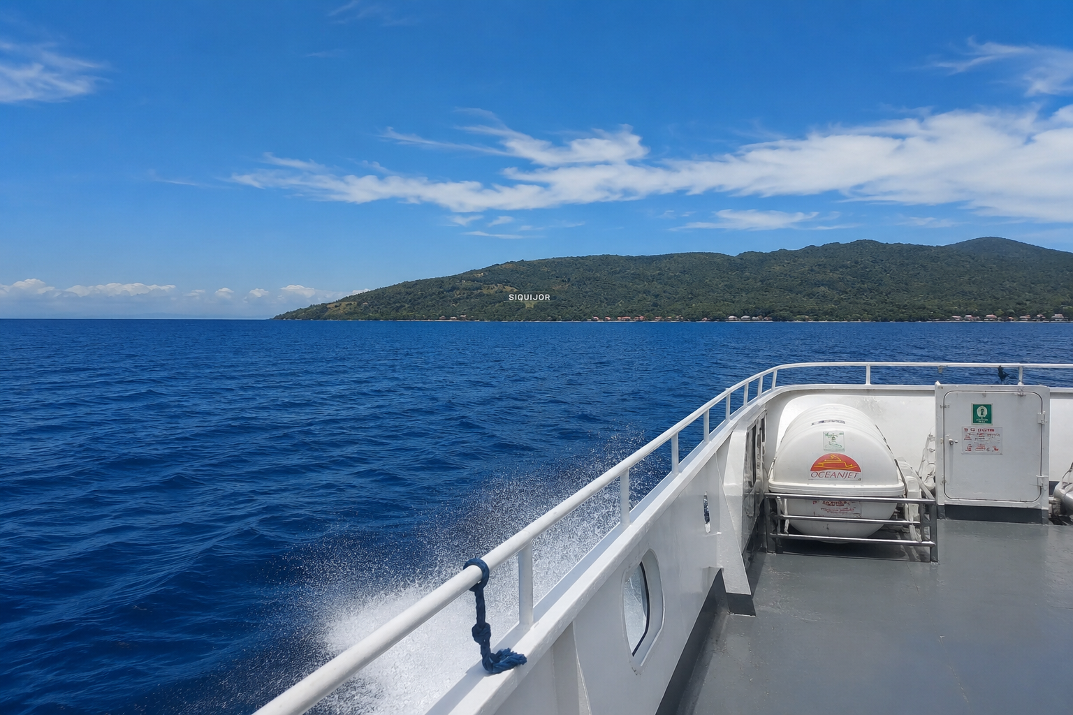 View from the deck of a fastcraft ferry crossing to Siquijor — open blue water and clear sky with Siquijor island visible on the horizon, Philippines