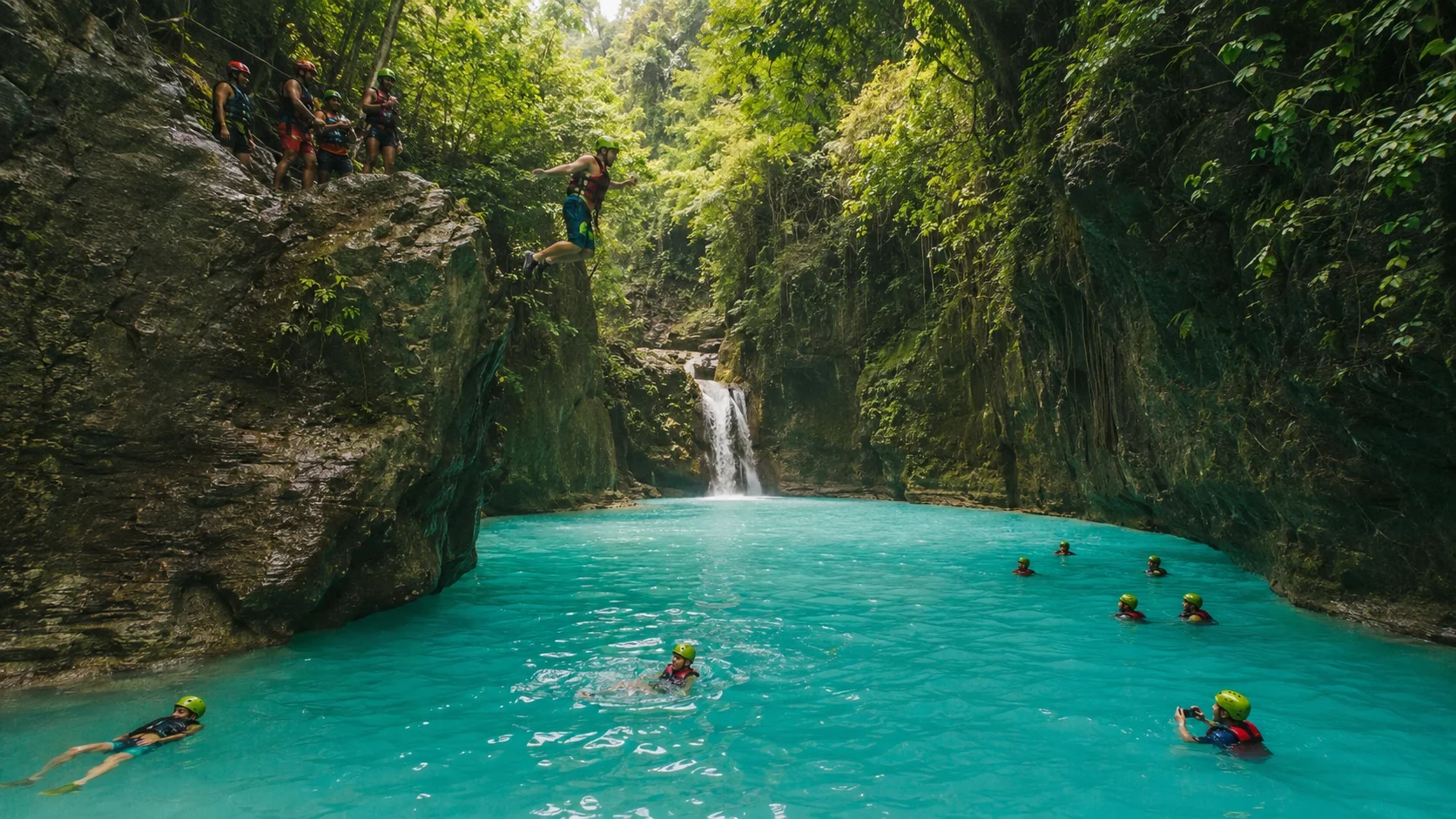 Kawasan Falls canyoneering Cebu — turquoise blue waterfall with canyoneers jumping off cliffs into the Gatorade-blue pools of the Kanlaob River in Badian, Cebu Philippines
