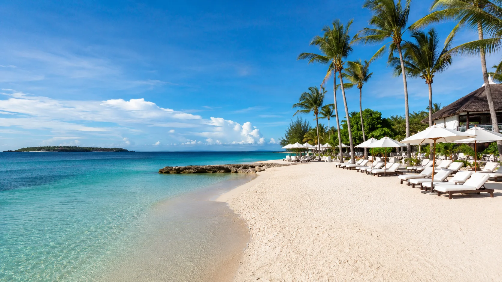 Mactan Island Cebu Philippines — luxury resort beach with crystal clear turquoise water, palm trees, and the resort strip at Punta Engano with Hilutungan island visible in the distance