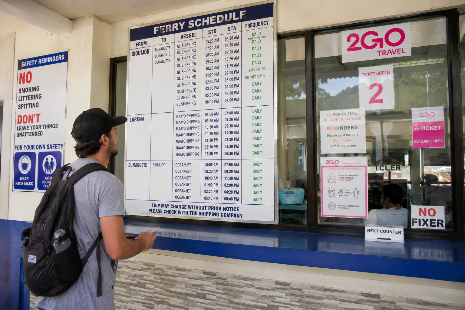 Traveler buying a ferry ticket at the port counter for Siquijor Philippines — showing the ticket booth and booking process at a Philippine domestic ferry terminal