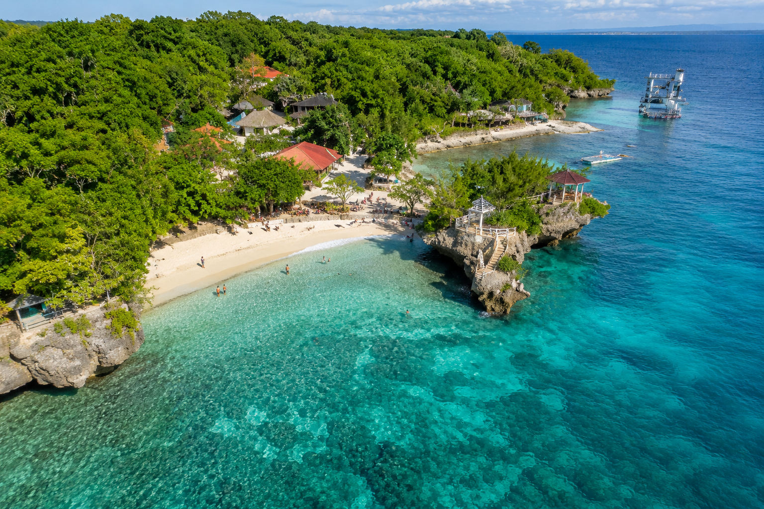 Salagdoong Beach Siquijor wide view — turquoise cove enclosed by pine trees with the famous wooden cliff diving platform visible on the right