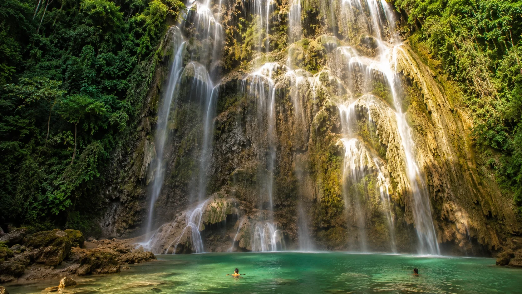 Tumalog Falls Oslob Cebu Philippines — multi-tiered curtain waterfall with mist rising into jungle greenery, 20 minutes from the Oslob whale shark site at Tan-awan